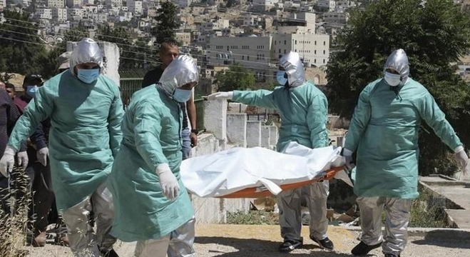 فريق طبي فلسطيني ينقل جثة أحد ضحايا فيروس كورونا